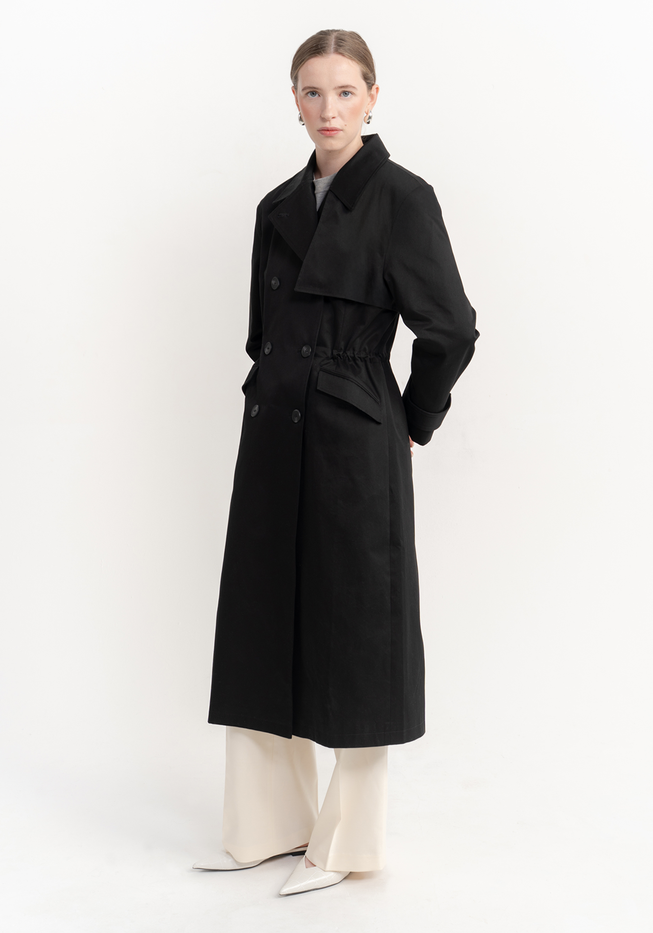 Woman wearing a black coat on a white background - front view