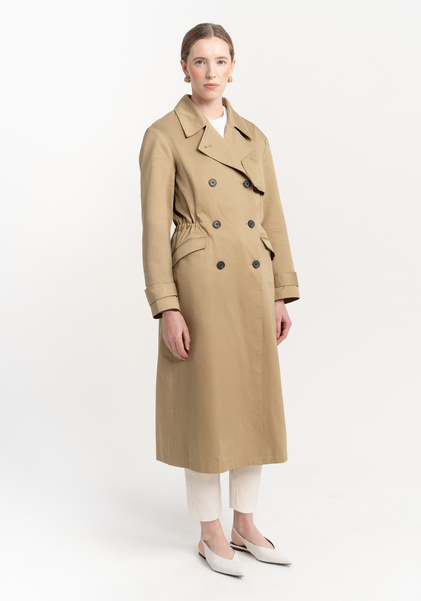 Woman wearing a beige trench coat on a white background
