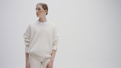 women model wearing a cream v neck jumper standing in a white studio